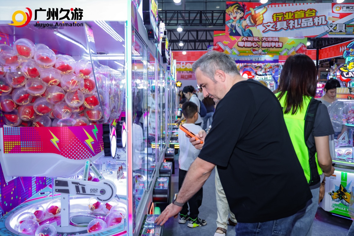 International buyer inspecting a Jiuyou capsule prize machine on the exhibition floor